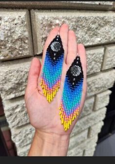 a person holding up some colorful beaded earrings