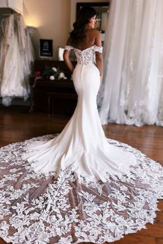 a woman in a wedding dress standing on a wooden floor with her back to the camera