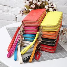 a stack of multicolored purses sitting on top of a table next to flowers