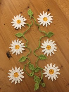 crocheted daisies are arranged on a wooden surface