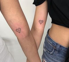 two women with matching tattoos on their arms, both holding each other's hands