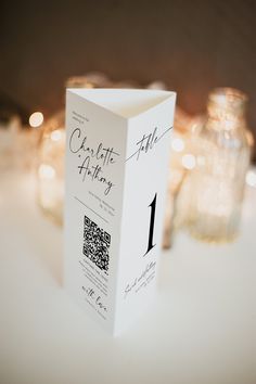 a close up of a white box on a table with candles in the back ground