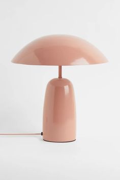 a pink table lamp sitting on top of a white surface