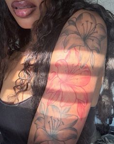 a woman's arm with flowers on it and the sun shining through her hair