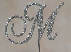 a cake topper with the letter m on it's side is made out of silver glitter