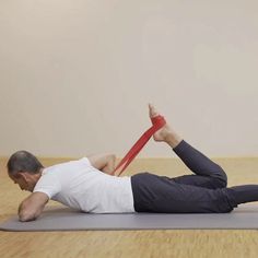 a man is doing yoga on a mat with a red strap around his ankles and feet