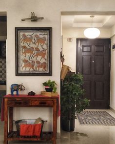 an entry way with a table, potted plant and pictures on the wall above it