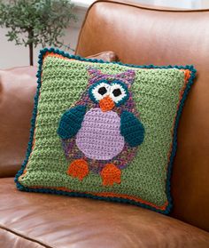 a crocheted owl pillow sitting on top of a brown couch