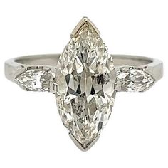 an oval cut diamond ring with three pear shaped diamonds on the shoulders and side stones