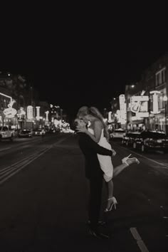 black and white photograph of couple kissing in the middle of an urban street at night