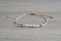 Natural moonstone string bracelet; simple string wish bracelet - Minimalist string bracelet with adjustable sliding closure. - Dainty rose gold plated stainless steel beads. - 4 mm round faceted tiny white moonstone beads. - Beige strong string. - A string bracelet is a symbolic gift to be offered to anyone, as a lucky charm bracelet - Ready to give it as a gift this bracelet comes wrapped in one nice jewelry bag. If you have any questions about this item please feel free to leave a message. If Delicate Adjustable White Friendship Bracelets, Dainty Jewelry With Sliding Knot And Round Beads, Delicate White Adjustable Friendship Bracelets, White Delicate Adjustable Friendship Bracelets, Dainty Resizable Rose Gold Jewelry, Elegant Adjustable Friendship Bracelets With Faceted Beads, Delicate Beaded Bracelet With Adjustable Chain, Elegant White Jewelry With Sliding Knot, Resizable Minimalist Rose Gold Jewelry