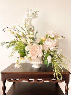 a white vase filled with flowers on top of a wooden table