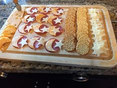 a wooden cutting board topped with cheese and crackers