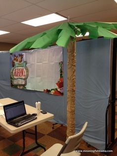 a laptop computer sitting on top of a table under a palm tree in an office