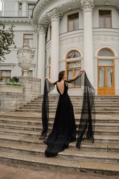 a woman in a black dress standing on some steps