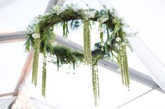 a wedding arch with flowers and greenery hanging from it's ceiling in a tent