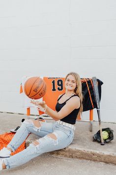 a woman sitting on the ground holding a basketball