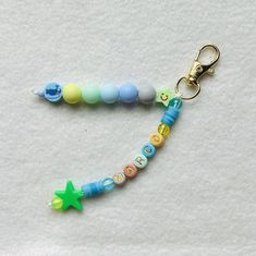 a pacifier keychain with beads and a star on the end is laying on a white surface