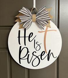 a door hanger that says he is risen with a bow hanging from the front