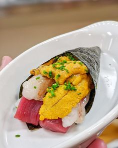 a person holding a white plate with sushi on it