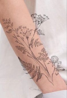 a woman's arm with flowers and leaves on it