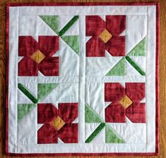 a quilted table topper with red and green flower designs on it's sides