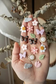 a person's hand holding several small flowers and butterflies on their thumbnails