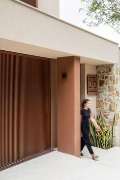 a woman walking past a tall brown building