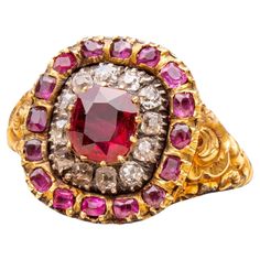 A superb antique Georgian ruby and diamond ring made in England, circa 1820. The centre of this ‘target’ shaped cluster ring is set with a 1ct cushion cut deep red ‘pigeon’s blood’ ruby, probably Burmese origin. Neatly prong-set, it is encircled by a halo of old cut diamonds in crimpled collet silver settings which is further surrounded halo of smaller cushion cut rubies. The ring is typical of early 19th century Georgian design with its intricate repoussé-work shoulders, decorated with roses an Georgian Rings Antique, Georgian Ring, Blood Ruby, Antique Jewelry Rings, Ruby And Diamond Ring, Small Cushions, Ruby Diamond, Antique Jewellery, Antique Rings