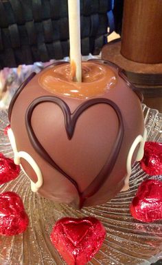 a heart shaped chocolate cake on a plate with candy hearts around it and a lit candle in the middle