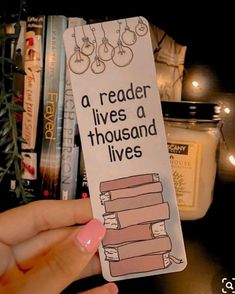 a person holding up a bookmark that says, a reader lives a thousand lives