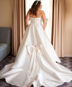 a woman in a wedding dress looking out the window