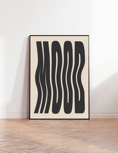 a black and white abstract art print on a wall in an empty room with hard wood flooring