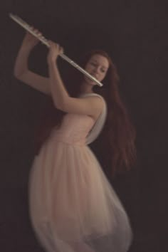 a woman in a pink dress holding a flute and posing for the camera with her long red hair