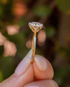 a close up of a person's hand holding a ring with a diamond on it