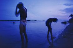 two people standing in the water at dusk