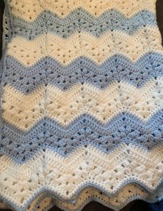 a blue and white crocheted blanket sitting on top of a couch