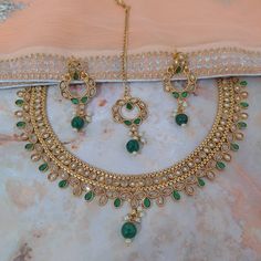 The gorgeous necklace set is beautifully handcrafted in gold plated, kundan Stones, pearls, beads. The beautiful kundan chand bali style earrings and maangtikka add to the traditional ethnicity of the piece. Main Colour: Gold Pearl Colour: Ivory, Green Stones Colour: Light Champagne, Green Length of the earrings: 5.5 cm / Width: 2.4 cm Necklace: Necklace with adjustable necklace cord to adjust the length of the necklace. Tikka Size: Small Kundan Bridal Necklace For Diwali Marriage, Kundan Bridal Necklace For Marriage During Diwali, Round Kundan Necklace For Marriage And Festivals, Kundan Necklace For Marriage And Festivals, Kundan Necklaces For Marriage, Kundan Necklace With Tilla For Marriage, Festive Hand Set Kundan Necklace For Marriage, Festive Kundan Jewelry For Marriage, Bollywood Kundan Necklace With Cutdana For Marriage