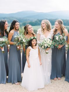 a group of women standing next to each other wearing dresses and holding bouquets in their hands