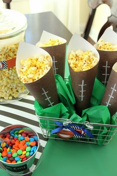 a table topped with lots of candy covered cones filled with footballs and marshmallows