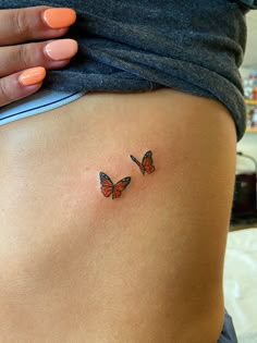 a woman's stomach with two small butterflies on the back of her lower body