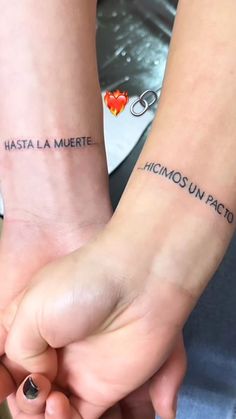 two people are holding hands with tattoos on their arms and the words in spanish above them