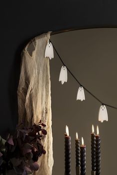 halloween decorations with candles and ghost heads hanging from the ceiling in front of a mirror