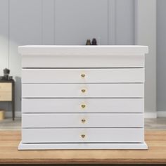 a white dresser sitting on top of a wooden table