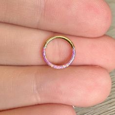 a person's hand with a gold ring on their finger and pink flowers in the middle