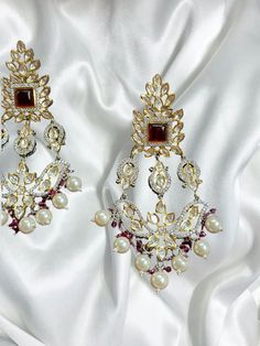 Introducing our exquisite Gold Indian Earrings adorned with radiant rubies and mesmerizing uncut polki, a true testament to timeless elegance and traditional craftsmanship. These captivating earrings are designed to enhance your beauty and add a touch of regal charm to any ensemble. 🌟 Features: 🔸 Material: High-quality gold-plated metal 🔸 Gemstones: Rich red rubies and sparkling uncut polki 🔸 Length: Gracefully long, these earrings dangle elegantly 🔸 Colors: Available in three enchanting sh Ruby Chandbali Earrings With Latkans, Elegant Kundan Jhumkas For Eid, Bollywood Style Ruby Chandbali Jhumkas, Festive Bollywood Ruby Chandbalis, Heavy Ruby Chandbalis, Elegant Red Jhumkas For Festive Occasions, Red Elegant Jhumkas For Celebration, Festive Temple Jewelry Ruby Danglers, Bollywood Ruby Danglers For Festive Occasions