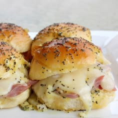 two ham and cheese sliders on a white plate with black pepper sprinkles