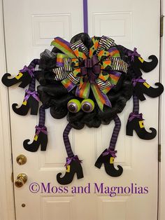 a halloween wreath on the front door decorated with googly eyes and purple ribbon bows