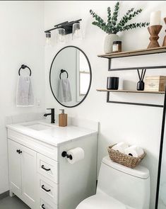 a white toilet sitting next to a bathroom sink under a mirror and a shelf with towels on it