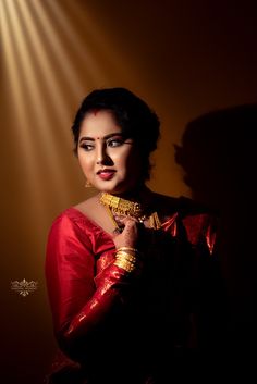 a woman in a red sari and gold jewelry poses for a photo with her hands on her chest